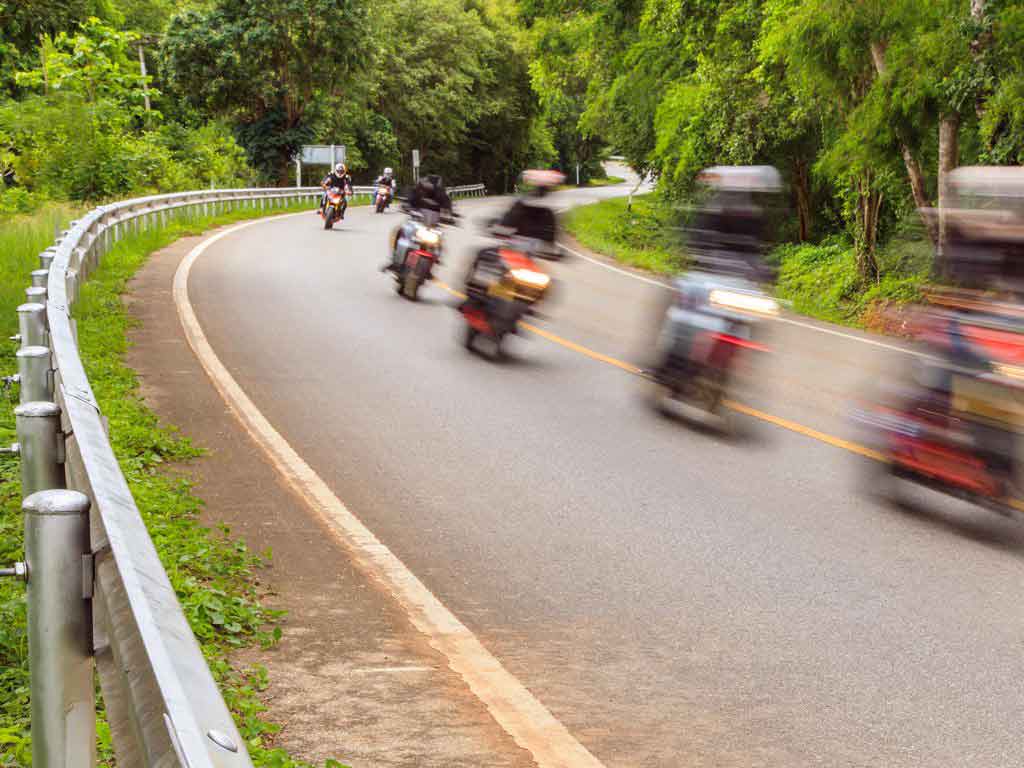 joukko moottoripyöräilijöitä ajaa jonossa maantiellä