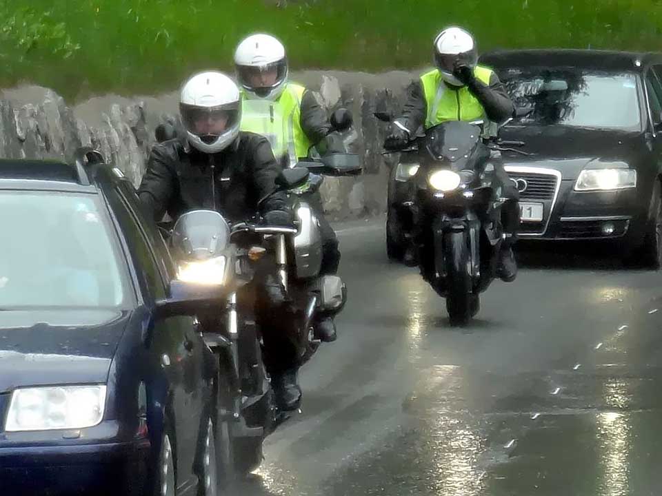 autoja ja moottoripyöriä liikenteessä sateisella kelillä