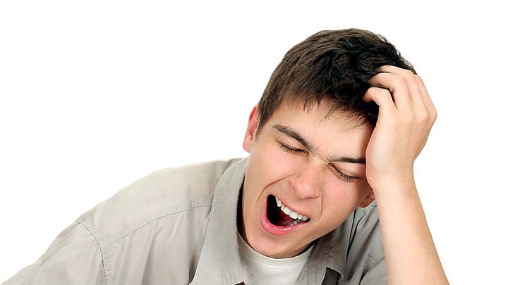 väsynyt henkilö nojaa päätään käteensä